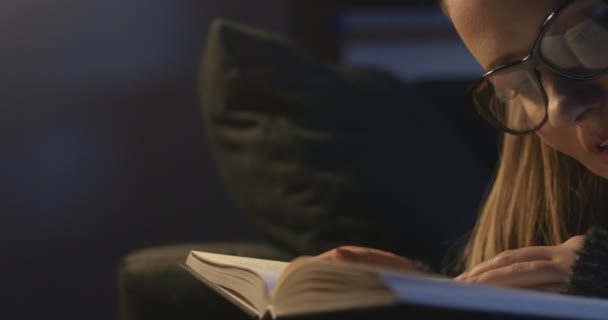 Mooie jonge vrouw lezen van een boek terwijl liggend op de Bank. — Stockvideo