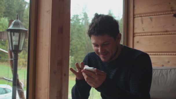 Junger hübscher Mann benutzt Smartphone zu Hause. — Stockvideo