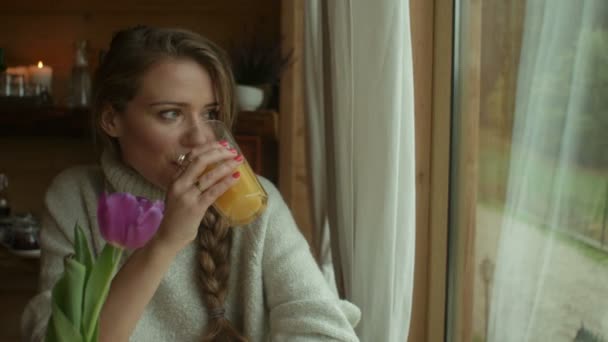 Retrato de cerca de una hermosa joven pensativa con jugo de naranja — Vídeo de stock