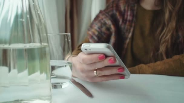 Руки женщины держат смартфон за столом . — стоковое видео