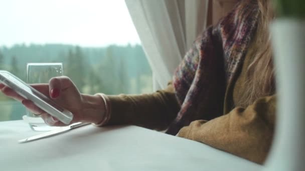 Vrouwelijke handen met een witte telefoon aan de tafel. — Stockvideo