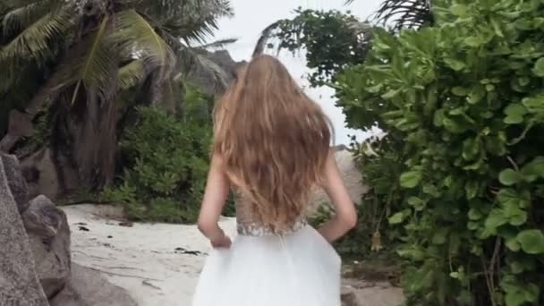Vackra glada kvinnan i vit brudklänning körs på tropical beach. — Stockvideo