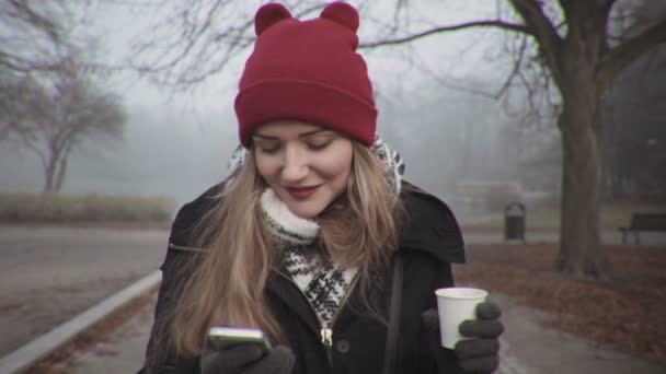 Γυναίκα με το κόκκινο καπέλο ψάχνει στο τηλέφωνο και χαμογελαστός. — Αρχείο Βίντεο