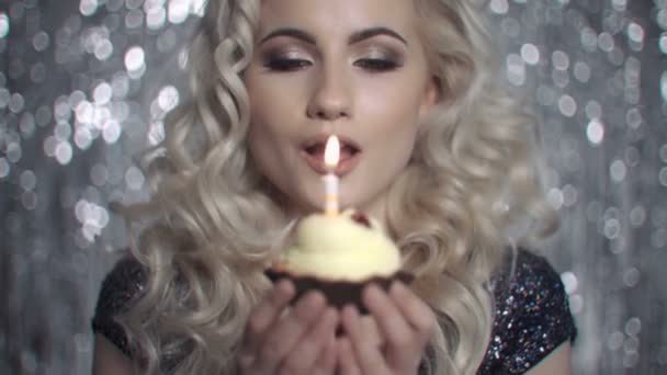 Blond kvinna blåser ljus på födelsedagstårtan. — Stockvideo