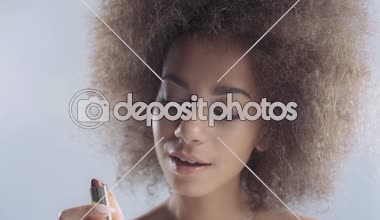 Güzel bir genç Afrikalı kadın ruj uygulama portresi.