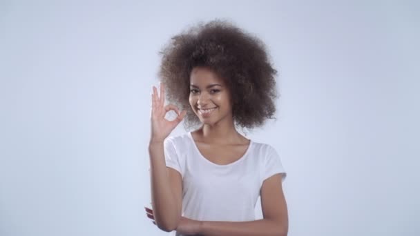 Mujer joven haciendo Ok signo sobre fondo blanco . — Vídeo de stock