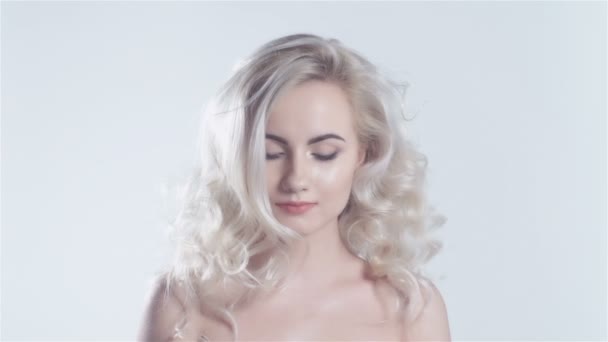 Beautiful blonde girl with healthy long curly hair smiling to a camera. — Stock Video