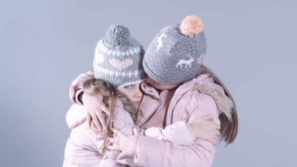 Cheerful little girls standing over white background and hugging each other. — Stock Video