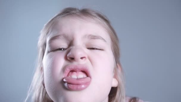 Niño joven sobresaliendo lengua, retrato sobre fondo gris . — Vídeo de stock