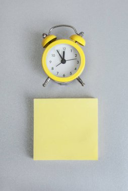 2021 yılının renkleri. Gri ve Sarı. Gri arkaplanda saati olan boş bir not, metin için boş yeri olan sarı çıkartma, kopyalama alanı. Soyut duvar kağıdı. Planlama konsepti, dikkat şablonu. 