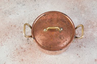 Beton bir arka planda kapağı ve pirinç saplı eski bakır güveç. Uzayı metin için kopyala. Yemek fotoğrafçılığı malzemeleri.