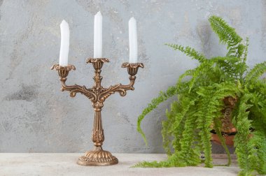 Beton zeminde üç mum için antika pirinç şamdan. Metin için alanı kopyala. 