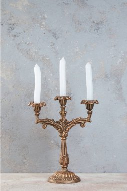 Beton zeminde üç mum için antika pirinç şamdan. Metin için alanı kopyala. 