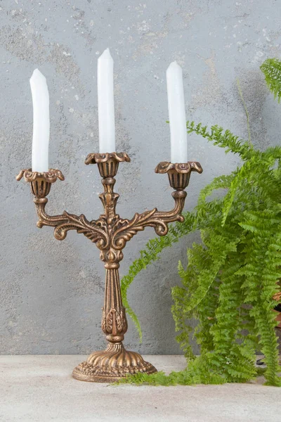 Beton zeminde üç mum için antika pirinç şamdan. Metin için alanı kopyala. 