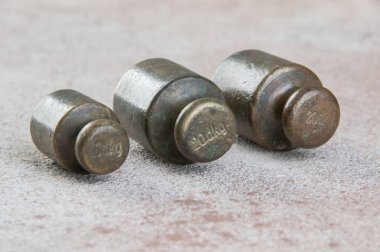 Beton arka planda pullar için üç antika bronz ağırlık. Metin ve yemek fotoğrafçılığı için alanı kopyala.