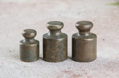 Beton arka planda pullar için üç antika bronz ağırlık. Metin ve yemek fotoğrafçılığı için alanı kopyala.