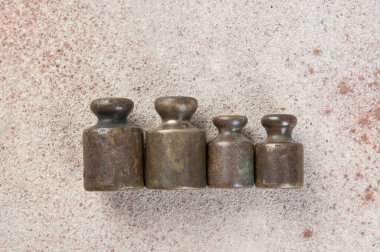 Beton arka planda pullar için dört antika bronz ağırlık. Metin ve yemek fotoğrafçılığı için alanı kopyala.