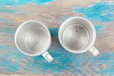 Ahşap arka planda iki eski alüminyum bardak. Metin için alanı kopyala