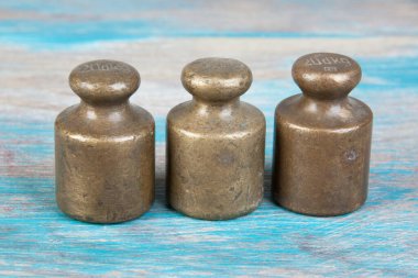 Mavi ahşap arka planda pullar için üç antika bronz ağırlık. Metin ve yemek fotoğrafçılığı için alanı kopyala.