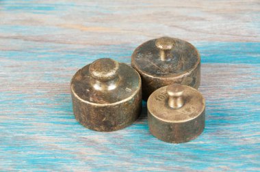Mavi ahşap arka planda pullar için üç antika bronz ağırlık. Metin ve yemek fotoğrafçılığı için alanı kopyala.