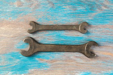 Eski mavi ahşap arka planda iki adet bronz İngiliz anahtarı. Metin için alanı kopyala.