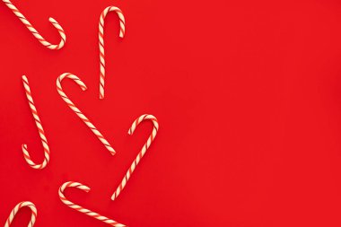 Noel bastonu şekerlemeleri, tatlı çubuklar, kırmızı arka planda kırmızı ve beyaz şekerler yazı için yeri olan düz yatıyordu. Tatil Xmas kavramı.