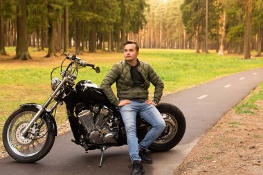 Güzel adam motosiklette, yolda oturuyor.