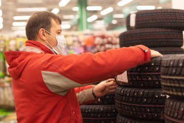 Adam kış lastiklerini ve arabayı izliyor.