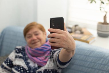 Mutlu yaşlı kadın evde selfie çekiyor.