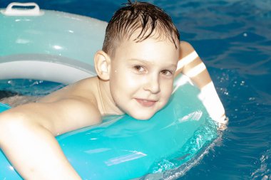 Güzel, mutlu çocuk havuzda yüzüyor.