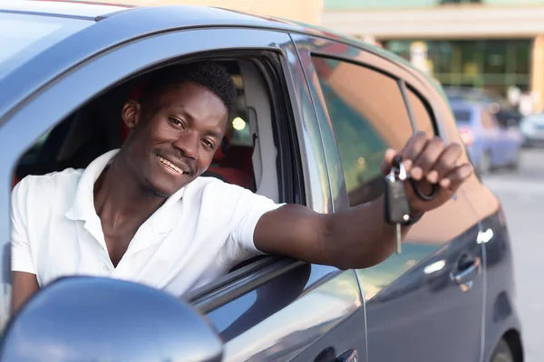 An African-American man holds a car key in his hands. Buying and renting a car.