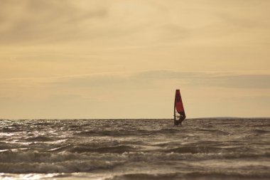 Sunset at sea. Windserfer is in the water.