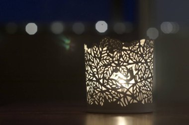 Arkaplanda Bokeh olan oyulmuş beyaz tealight tutucu