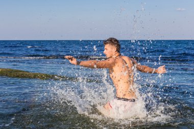 çıplak genç adam sevinç için atlama bakınız su