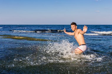 çıplak genç adam sevinç için atlama bakınız su