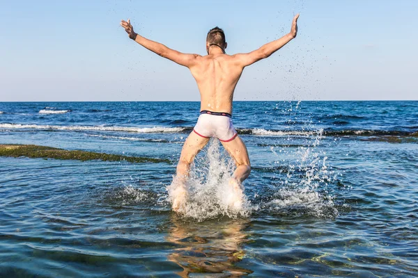 çıplak genç adam sevinç için atlama bakınız su