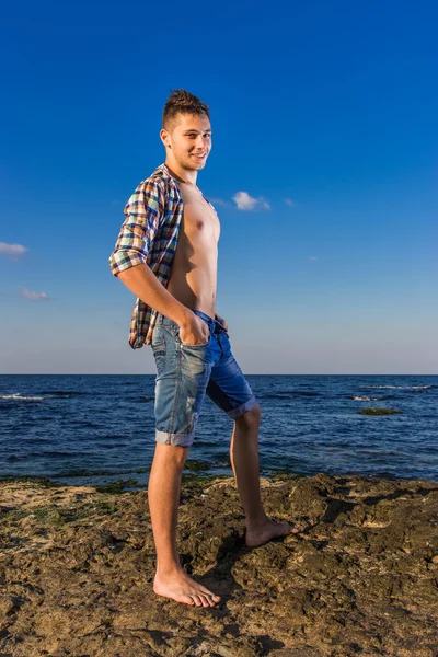 çekici genç moda seksi adam deniz suyu yakınındaki kayaya