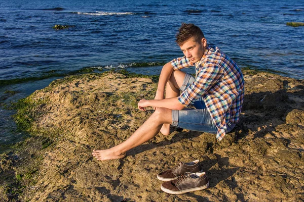 Προκλητικό άτομο ελκυστικό νεαρό μόδας σε βράχο κοντά στο νερό της θάλασσας Royalty Free Φωτογραφίες Αρχείου