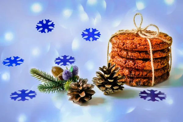 Ev yapımı kurabiyeler. Beş tatlı yulaf ezmeli kurabiye katlanır ve Noel arkaplanında keten bir iple bağlanır. Bokeh, kar taneleri ve köknar kozalaklarıyla süslenir. Şenlikli ve Noel atmosferi.
