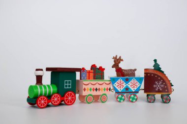 Oyuncak tahta bir Noel treni, kış tatilinin özelliklerini beyaz arka planda taşır. Dekoratif Noel tatili konsepti. Kopyalamak için boş alan.