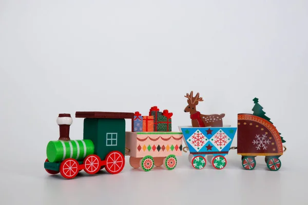 Oyuncak tahta bir Noel treni, kış tatilinin özelliklerini beyaz arka planda taşır. Dekoratif Noel tatili konsepti. Kopyalamak için boş alan.