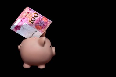 Siyah arka planda 100 Yuan 'lık banknot olan bir kumbara. Tasarruf kavramı. Dikkatli yatırım. Risksiz finansman. Tasarruf ve finans. Boş alan