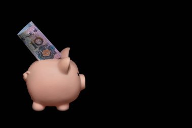 Siyah arka planda 10 Yuan 'lık banknot olan bir kumbara. Tasarruf kavramı. Dikkatli yatırım. Risksiz finansman. Tasarruf ve finans. Boş alan