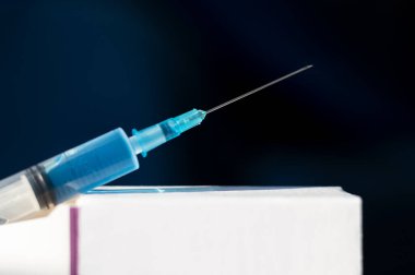 Aşıyla hazırlanmış şırınga beyaz bir karton kutunun üzerinde duruyor. Yakın plan. Boş alan. Bulaşıcı hastalıkların önlenmesi, aşılanması ve tedavisi konsepti