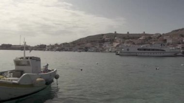 Chalki / Halki Adası, Yunanistan - 25 Eylül 2020: Yunanistan 'da seramik kaplamalı çatılar ve tepede inşa edilmiş ahşap pencerelere karşı motorlu tekne ve yolcu gemisinin Pan çekimi. düz derecelendirilmemiş