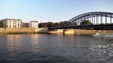 Krakow, Polonya: Altın saat boyunca modern Footbridge 'in altında seyreden bir motorlu tekne. Eski kasabada Polonya mimarisi