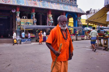Madurai, Hindistan - 02 Kasım 2018: Turuncu Hindu geleneklerine göre yaşlı bir adam elinde sopayla Thiruparankundram Murugan veya Subramanya Swamy adlı bir Hindu tapınağının önünde yürüyor.