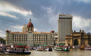 Mumbai, India: Wide angle shot of Gateway of India and Taj hotel against sea and dramatic cloudy sky