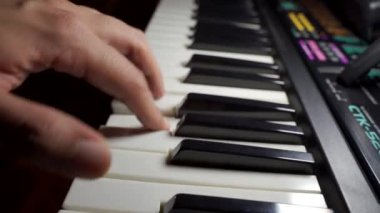 Seçici odak, hızlı piyano çalan bir erkeğin yakın çekimini gösteriyor. Müzik sanatçısı enstrüman çalıyor