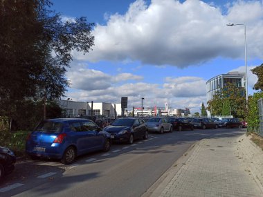 Krakow, Poland - March 17, 2021: Bunch of cars parked by the sidewalk on a narrow street against dramatic clouds during daytime